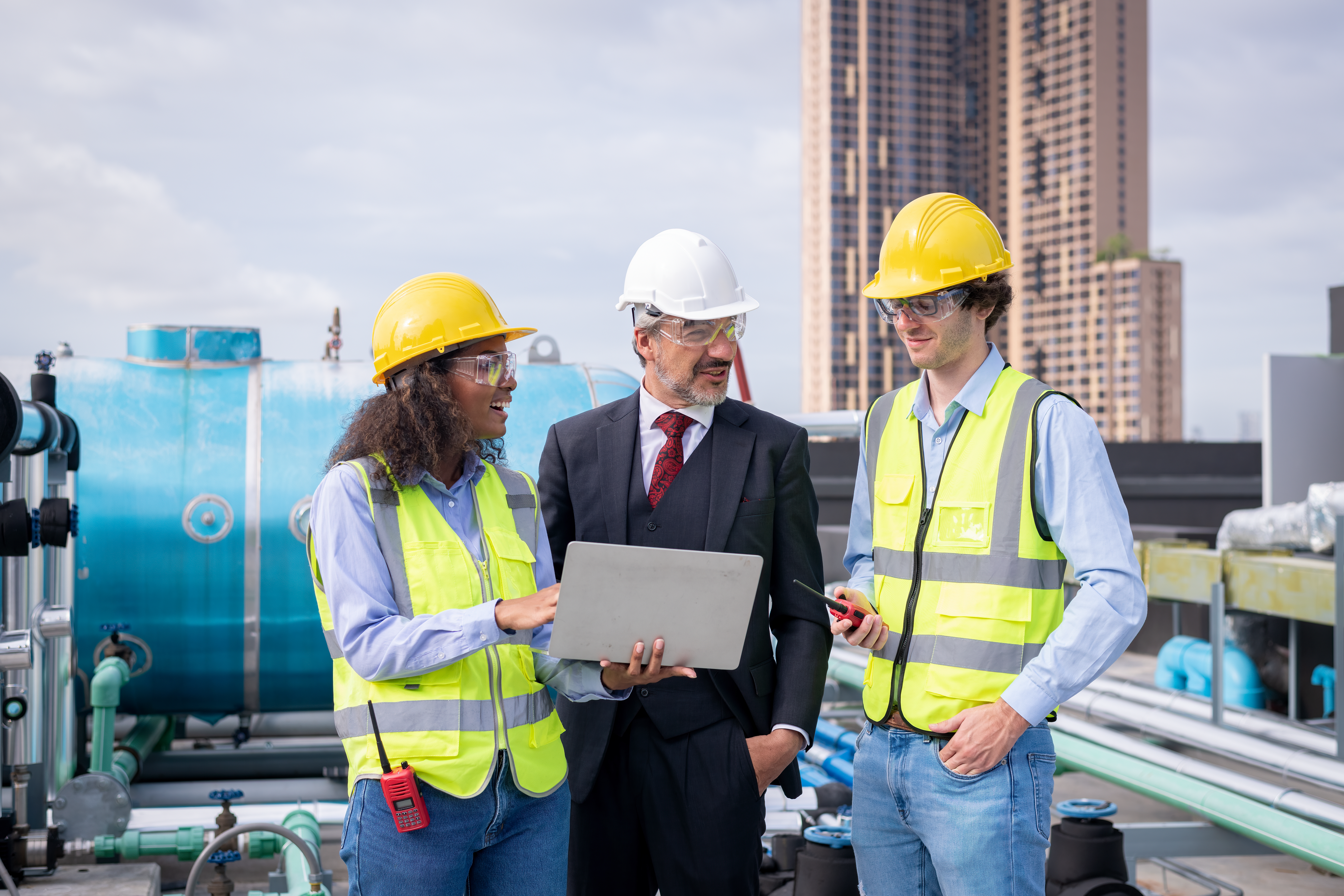 Manager and Engineers holding blueprint project under checking building cooling tower air conditione
